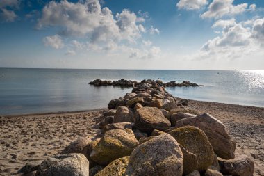 Güneşli bir sabahta dalgalı bir suyun seçici taşları