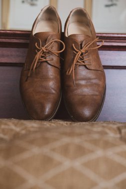 Bir çift kahverengi deri ayakkabının dikey görüntüsü.