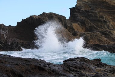 Güneşin altında, kayalık kıyılarda dalgalı bir su kütlesi.