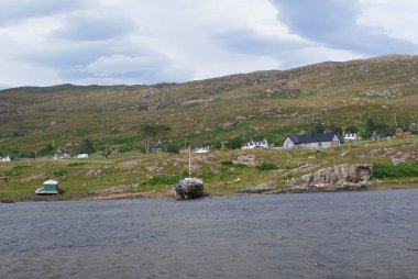 İskoçya 'daki dağların arka planında kıyıda park etmiş bir geminin güzel bir görüntüsü..