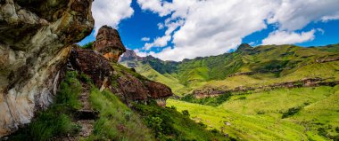 Bulutlu arka planda yeşil dağlık bir manzaranın manzarası