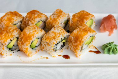 Beyaz arka planda beyaz bir tabaktaki suşi setine yakın plan.