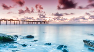 Güzel, pembe bir gün batımı gökyüzü mavi sularda bir limanın üzerinde