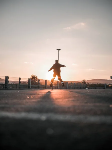 夕阳西下 一个跳伞男孩在人行道上的一张垂直的照片 — 图库照片