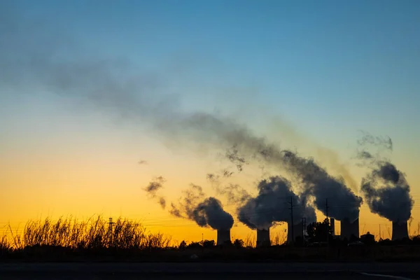 夕暮れ時に工場の煙突が煙を吹いている風景 — ストック写真