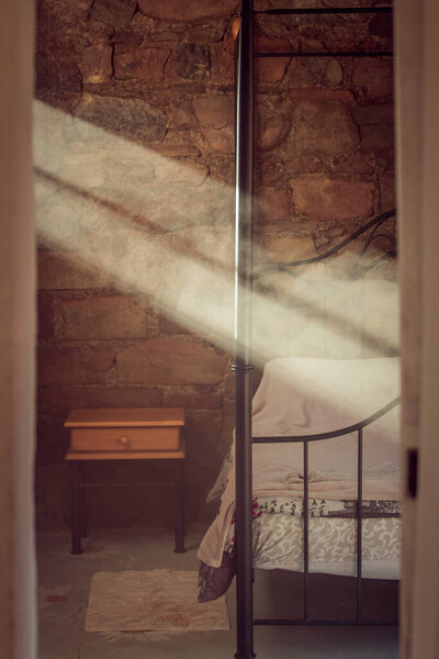 A vertical shot of a bedroom interior with sunbeams