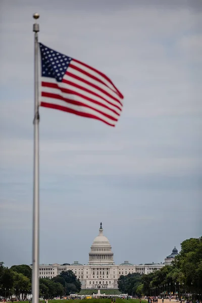 曇った空の下で米国の旗の後ろにあるキャピトルの美しい景色 — ストック写真