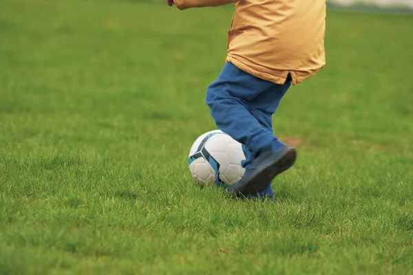 Niño Jugando Con Una Pelota Fútbol Campo Verde Imagen de archivo