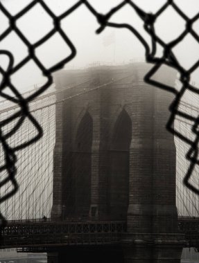 Brooklyn Köprüsü 'nün dikey gri tonlu görüntüsü, tel örgüdeki bir delikten alındı.