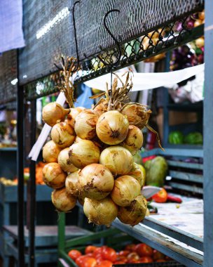 Bir markette asılı duran beyaz soğan kümesinin dikey yakın çekimi.