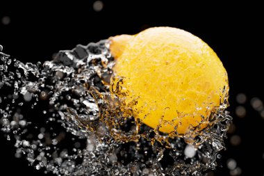 Koyu arkaplana su sıçratan limonu yakın çekim..