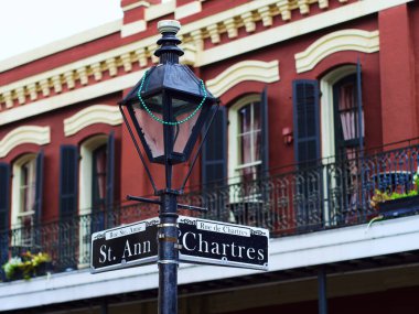 Kırmızı bir binaya karşı sokak lambası üzerinde Chartres St. Ann yazan bir tabelanın yakın çekimi. New Orleans, Louisiana.