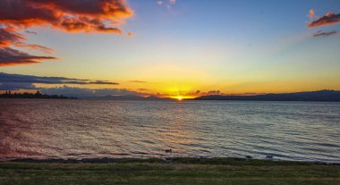 Gün batımında sahile yakın su dalgaları olan bir deniz manzarası.