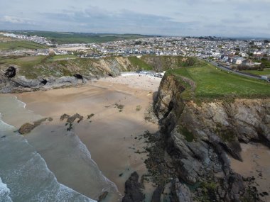 Bulutlu arka planda bir şehrin yanındaki sahilin manzarası.