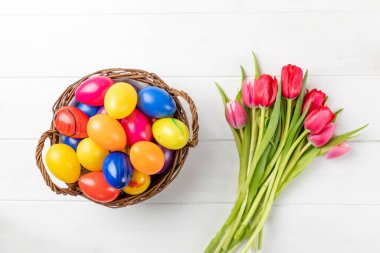 Beyaz arka planda renkli yumurtaları ve laleleri olan bir Paskalya yuvasına yakın çekim.