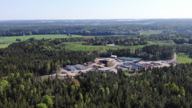 Yeşillik bir ormanın ortasında köknar ağaçlarıyla dolu bir inşaat alanının havadan görünüşü.