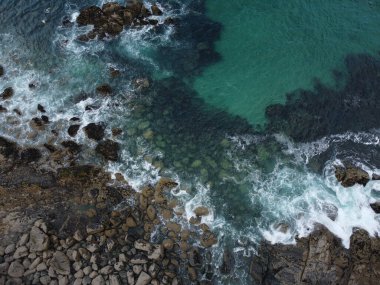 Kayalık bir sahili olan mavi bir okyanus manzarası.