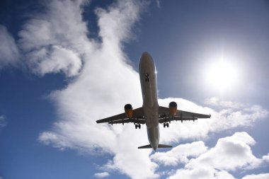 Bulutlu mavi bir arka planı olan bir yolcu uçağının alçak açılı görüntüsü.