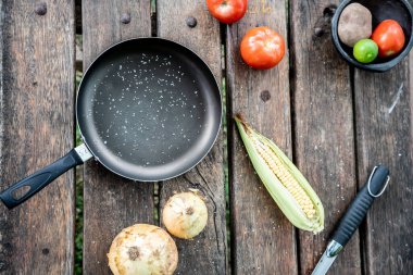 Tahta masada bir tava ve sebze.