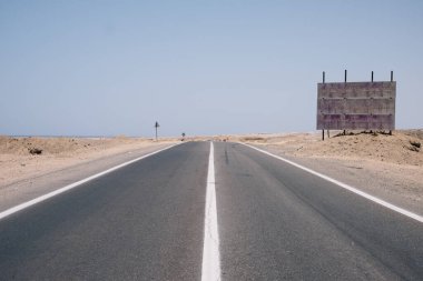 Mısır 'da mavi bir gökyüzü arka planında Sahra Çölü' nden geçen bir yol