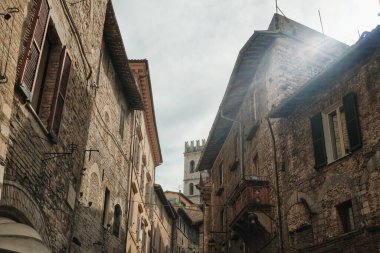 Assisi, İtalya 'da bulutlu bir gökyüzüne bakan pencereli eski tuğla binalar.