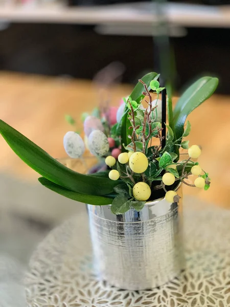 Renkli yumurta ve yeşil yapraklardan yapılmış bir Paskalya buketinin dikey çekimi.