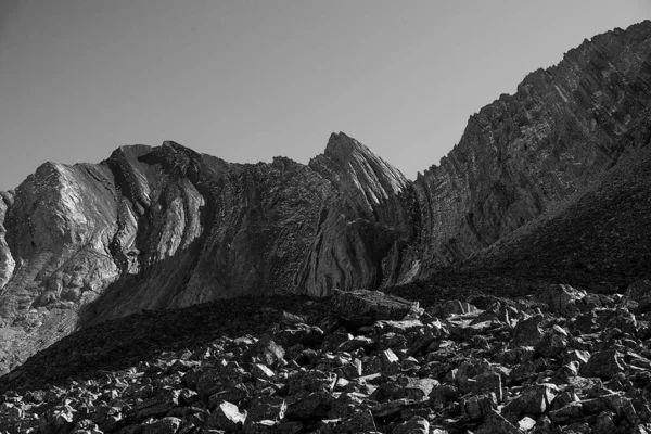 一个灰度低的低倾角的大悬崖 底部有岩石 — 图库照片