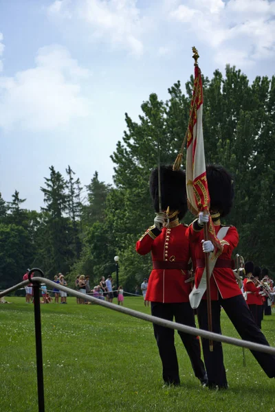 カナダの公園の緑の芝生の上に立って旗を持っている2人の王室のガイドの垂直ショット — ストック写真