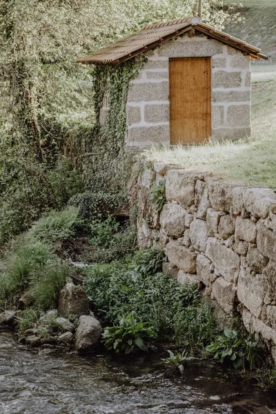 小石屋河边有一个木门 上面种满了绿色植物的古老的小石屋 — 图库照片