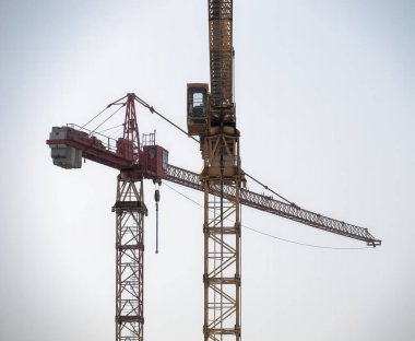 İki sarı ve kırmızı kule vinci parlak bir gökyüzüne karşı bir inşaat alanında