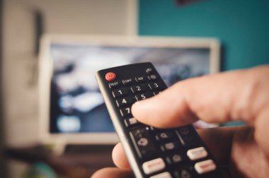 Uzaktan kumandayı televizyona çeviren bir el.