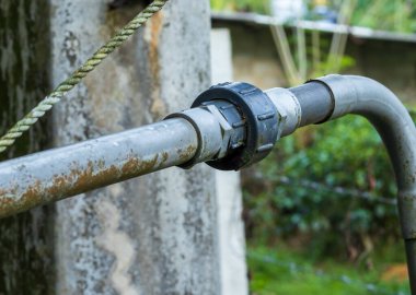 Yeşil bir bahçede iki tüpü birbirine bağlayan yakın çekim.