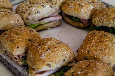 Bir tepside lezzetli, küçük jambonlu sandviçler.