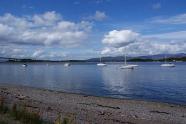 İskoçya 'da bulutlu bir gökyüzünün altında kumlu kıyı ve dağ manzarası