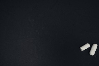 Boş bir siyah yüzey üzerindeki iki beyaz tebeşir parçasının üst görüntüsü
