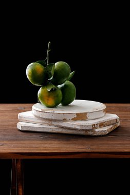 Siyah bir arka planda izole edilmiş beyaz bir masa üzerindeki yeşil mandalinaların dikey görüntüsü.