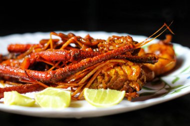 Siyah bir arka planda limonlu lezzetli bir ıstakoz körisinin yakın çekimi.