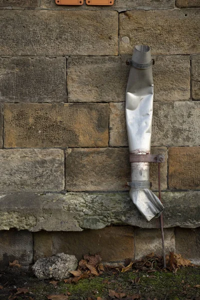 建物の上に雨水用に作られた壊れた金属パイプの垂直ショット — ストック写真