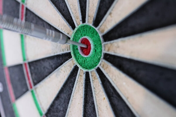 A closeup shot of a dart thrown directly at the center of a target - concept of reaching goals