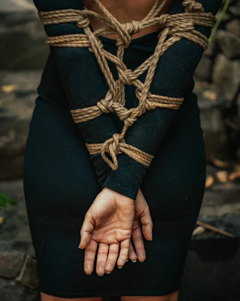 A vertical shot of the tied hands of a woman with a black dress in Guatemala