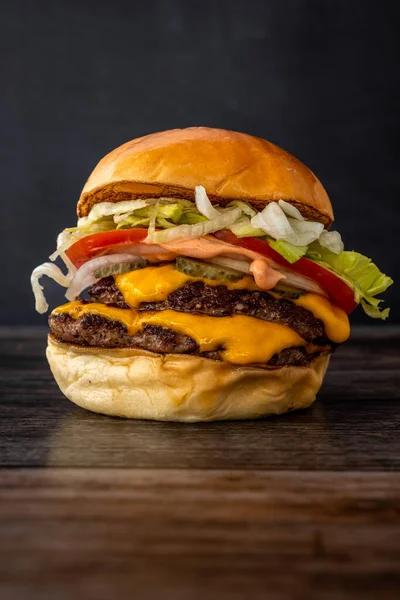 Pionowe Ujęcie Pysznego Soczystego Burgera Warzywami Drewnianym Stole — Zdjęcie stockowe