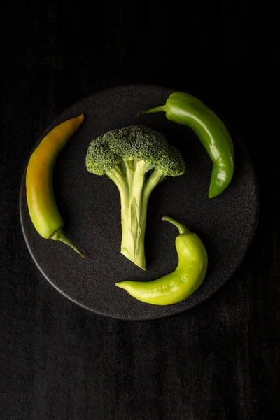 Een Verticaal Shot Broccoli Met Peper Een Zwarte Plaat — Stockfoto