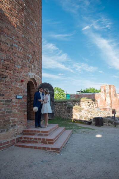 Целующая новобрачная кавказская пара, стоящая на боковой двери старой кирпичной церкви
