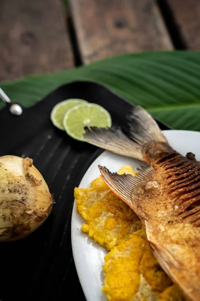 Tiro Vertical Peixe Cozido Bananas Fritas Uma Placa Uma Mesa — Fotografia de Stock