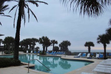 Güneşli bir günde bir tatil köyünde büyük bir açık havuz.