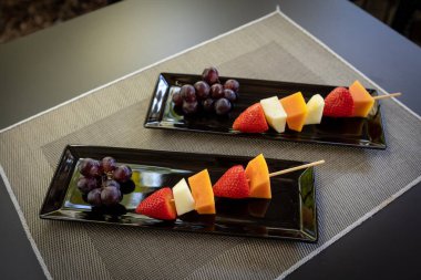 Dikdörtgen şekilli tabaklar üzerinde tahta çubuklar üzerinde taze kesilmiş meyvelerin açı çekimi..