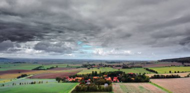 Almanya 'da tarlaları ve otlakları olan küçük bir köyün üzerindeki bulutlu bir gökyüzü.