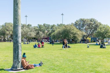 Bir grup insan Lizbon, Portekiz 'deki bir parkta güneşleniyorlar.