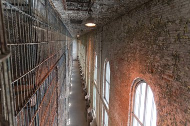 Paslı duvarları olan eskimiş bir hapishanede uzun bir koridor.