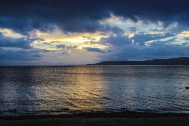 Gün batımında arka planda su dalgaları olan bir deniz manzarası.